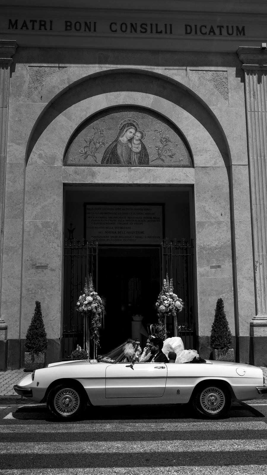 Gli sposi su una spider d'epoca davanti alla chiesa, in bianco e nero