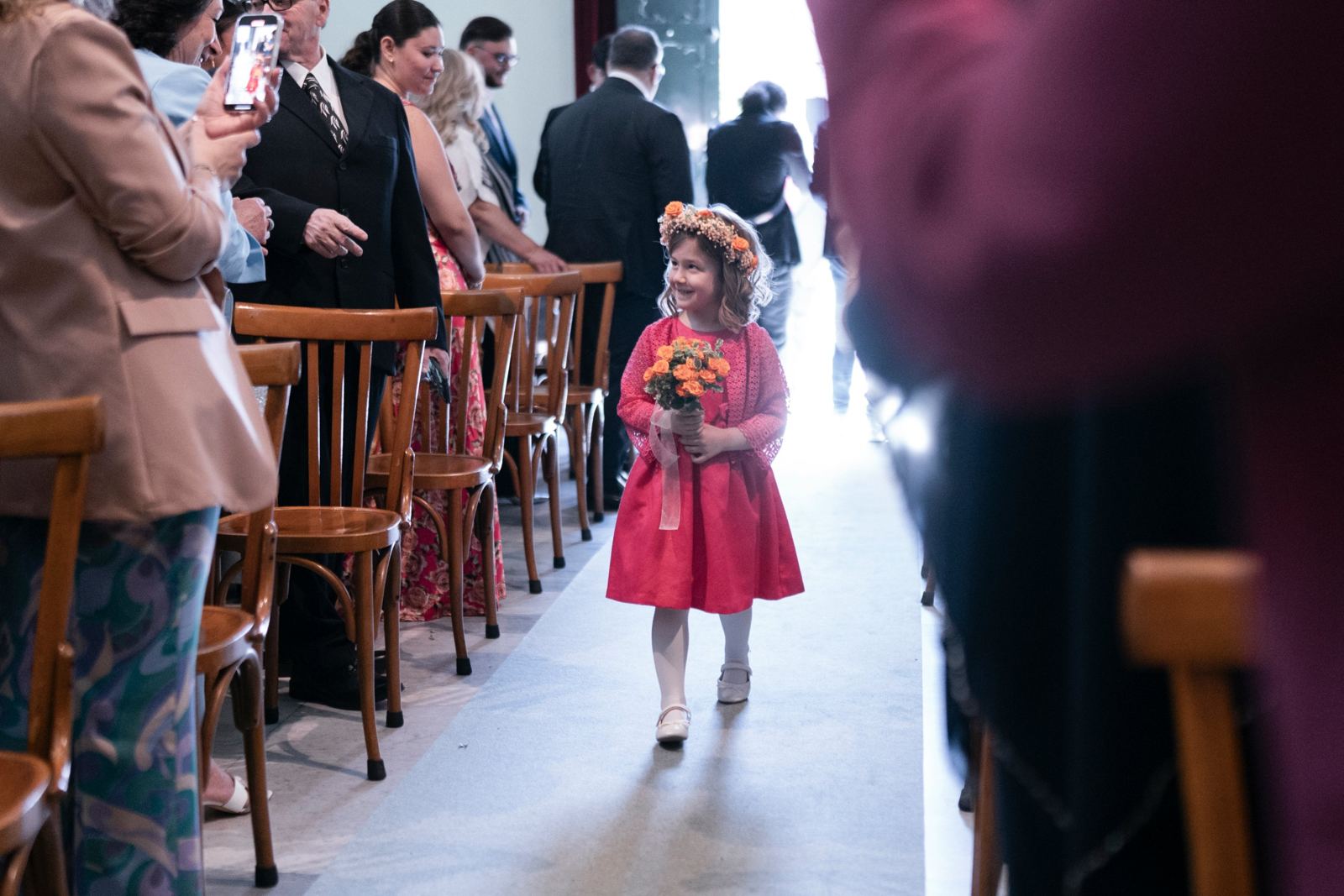 Una bambina con la coroncina di fiori percorre la navata