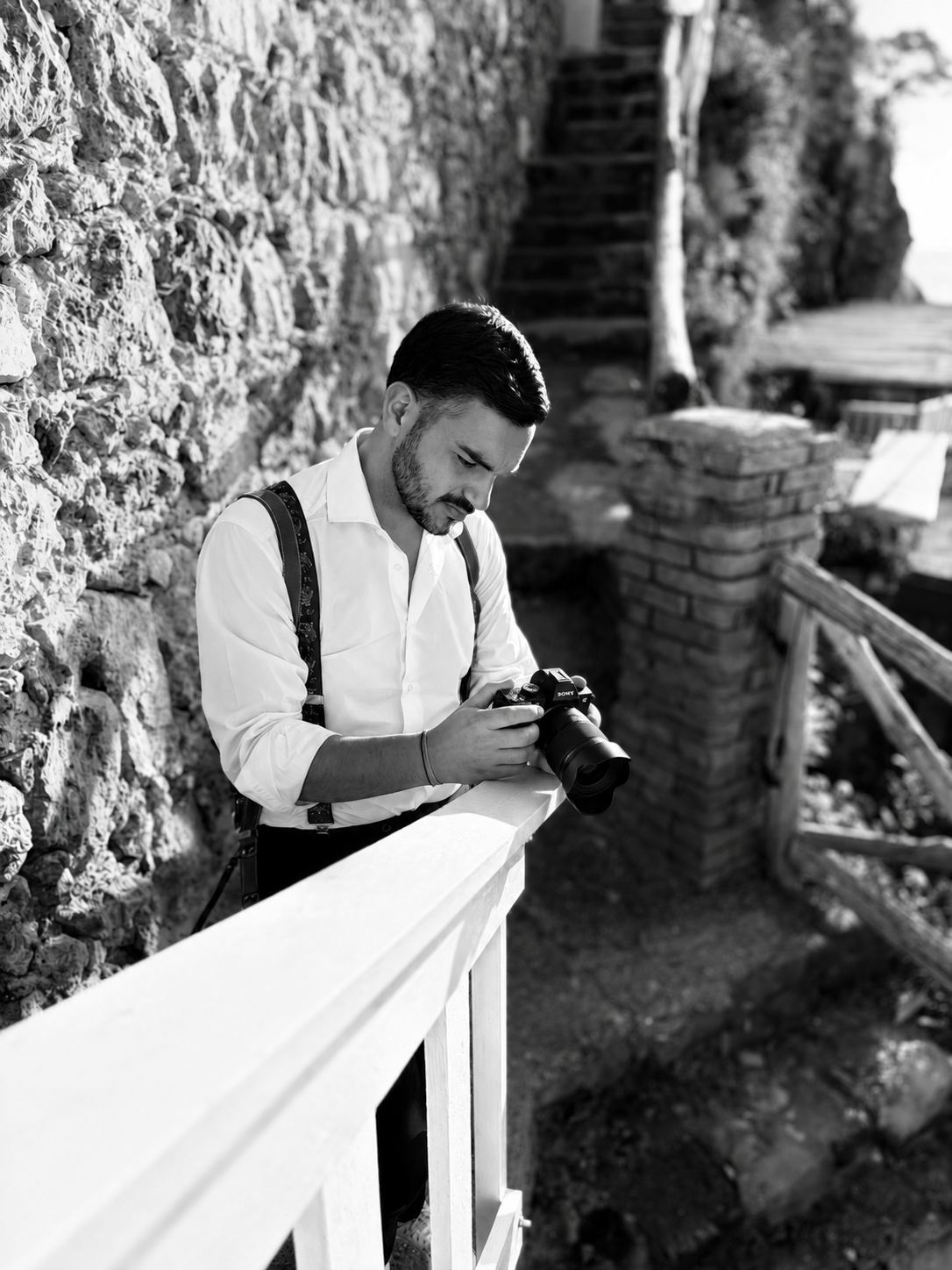 Francesco controlla gli scatti sulla macchina fotografica, appoggiato a una ringhiera
