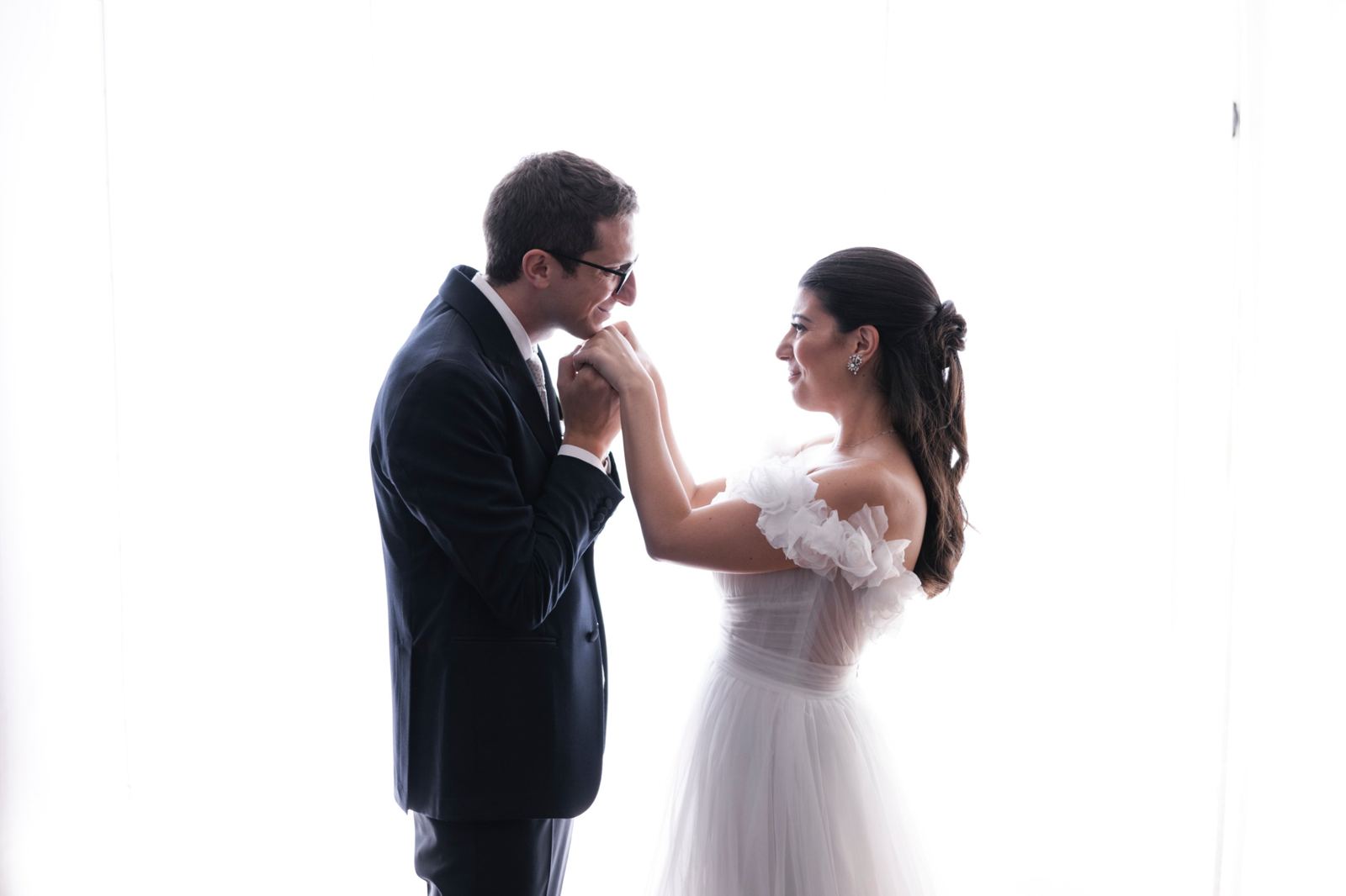 Lo sposo bacia la mano della sposa controluce, prima della cerimonia