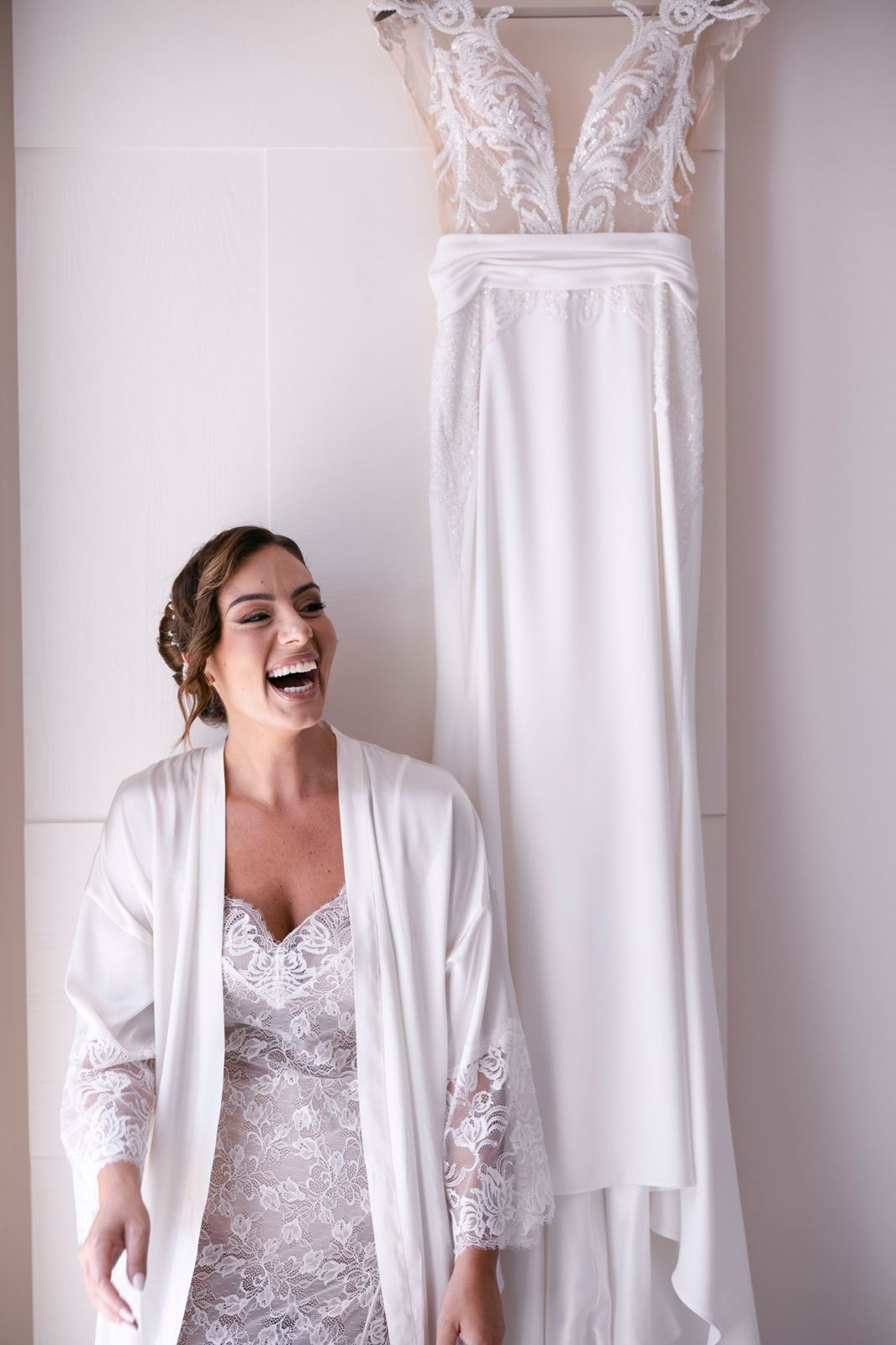 La sposa ride accanto al suo abito appeso