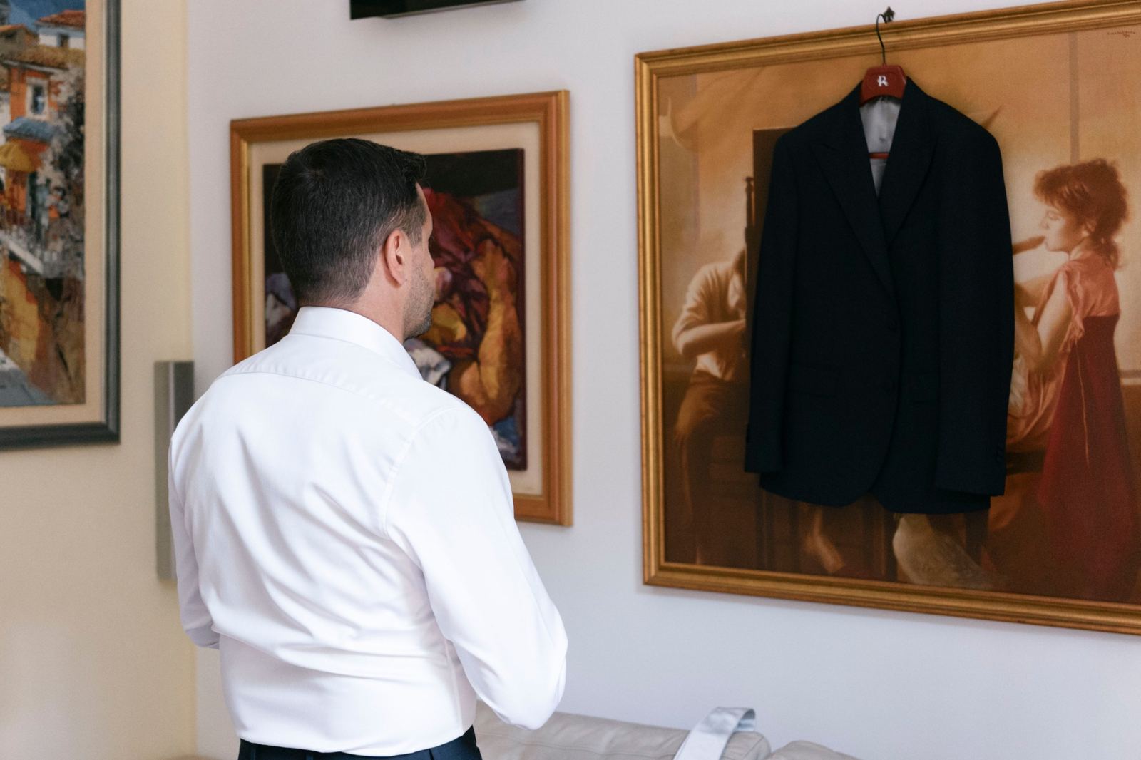 Lo sposo guarda la giacca appesa a un quadro