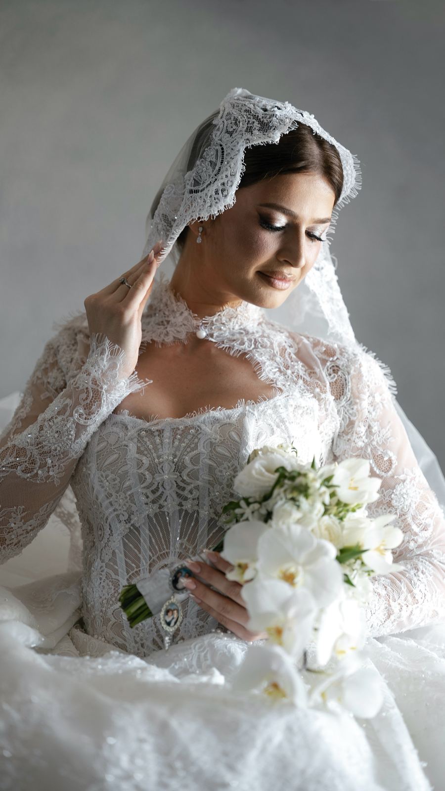 La sposa con il velo di pizzo e il bouquet di orchidee