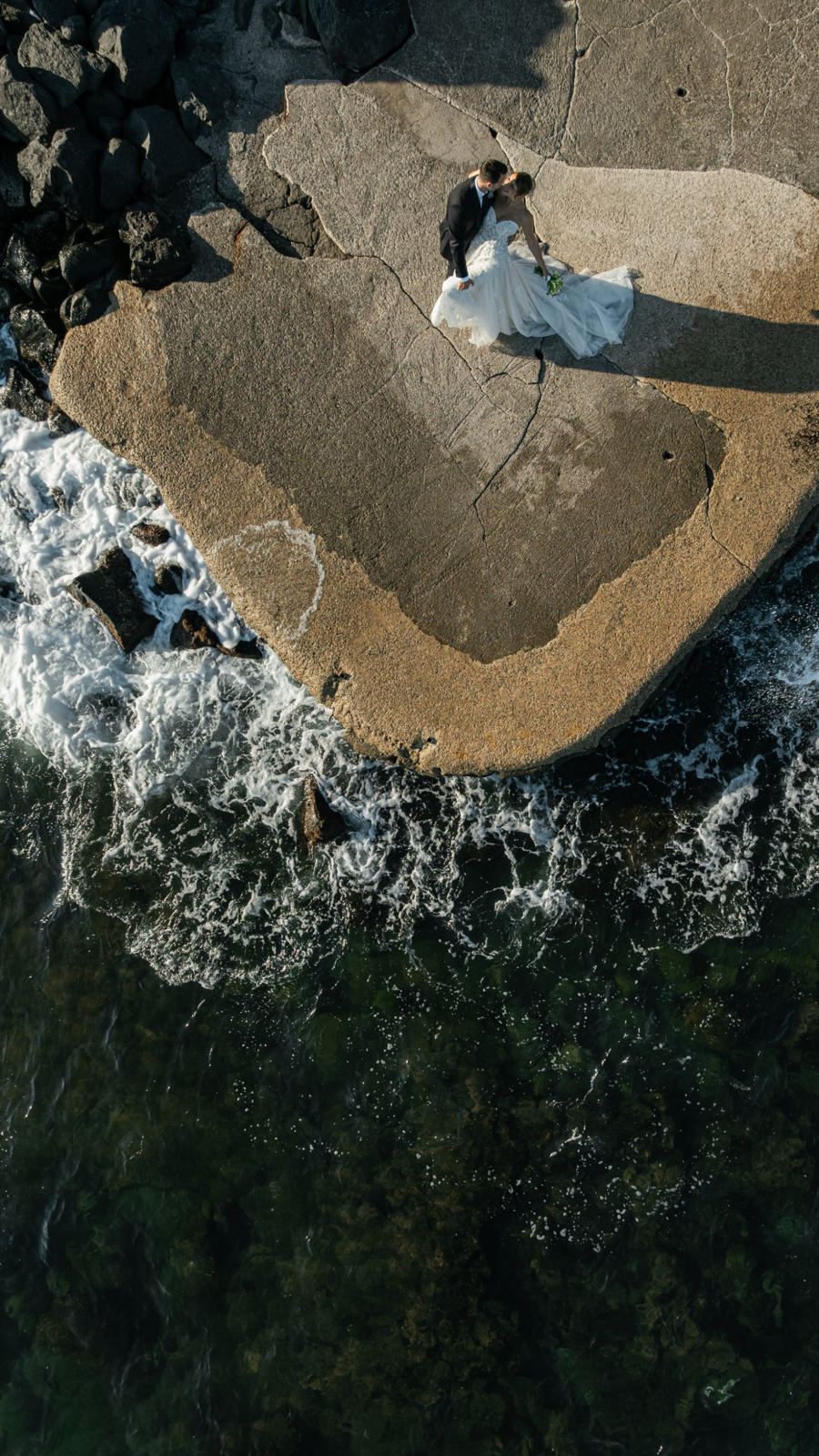 Gli sposi ripresi dal drone su uno scoglio, tra le onde